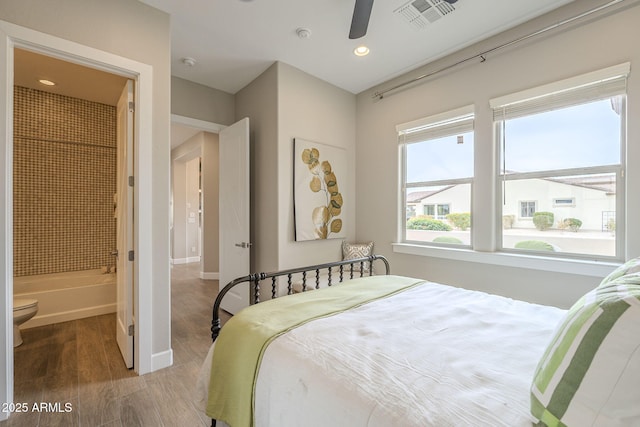 bedroom featuring wood finished floors, visible vents, baseboards, recessed lighting, and ensuite bathroom