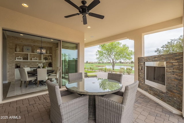 view of patio with an outdoor stone fireplace, outdoor dining area, and ceiling fan