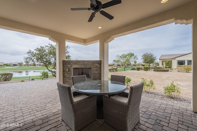 view of patio / terrace with a water view, outdoor dining space, and a ceiling fan