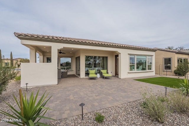 rear view of property with an outdoor living space, stucco siding, ceiling fan, and a patio area