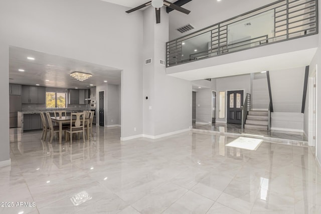 unfurnished living room with a high ceiling and ceiling fan