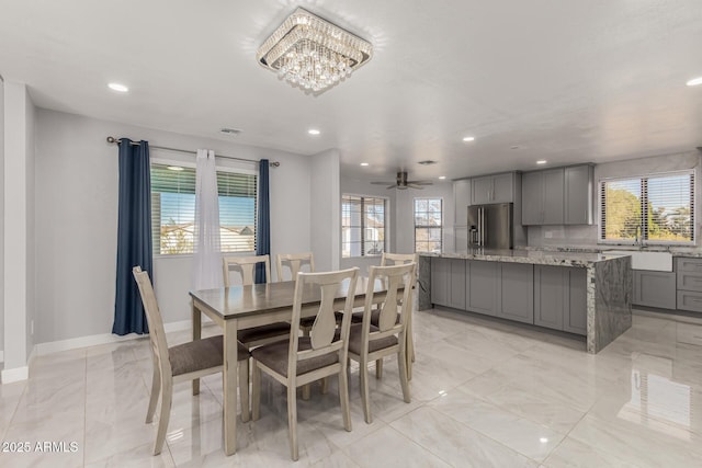 dining room with sink and ceiling fan with notable chandelier