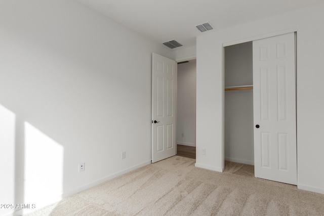 unfurnished bedroom with light colored carpet and a closet