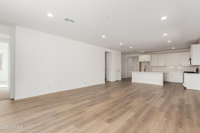 unfurnished living room with sink and light wood-type flooring