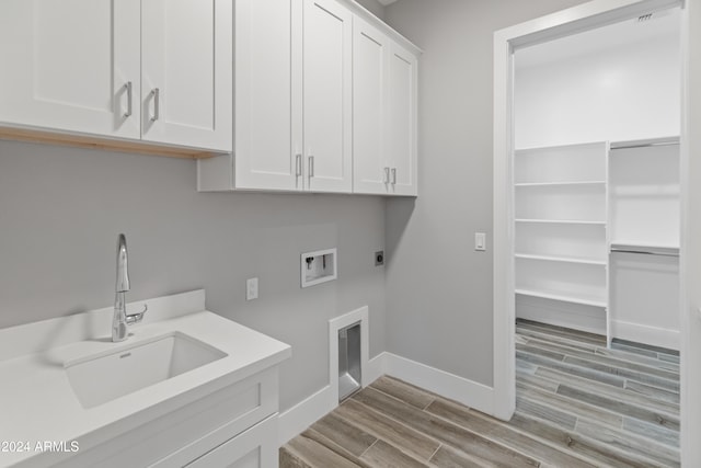 laundry area with electric dryer hookup, washer hookup, sink, light wood-type flooring, and cabinets