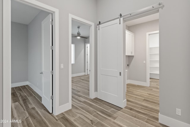 corridor with a barn door and light hardwood / wood-style floors