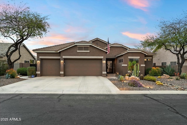 view of front of home featuring a tile roof, concrete driveway, a garage, and stucco siding