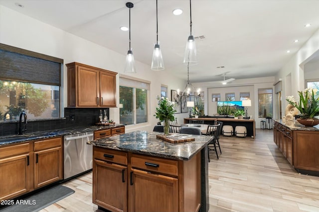 kitchen featuring a sink, backsplash, a center island, dark stone counters, and dishwasher