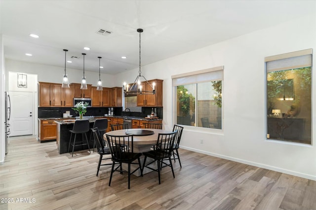 dining room featuring baseboards, visible vents, light wood finished floors, an inviting chandelier, and recessed lighting