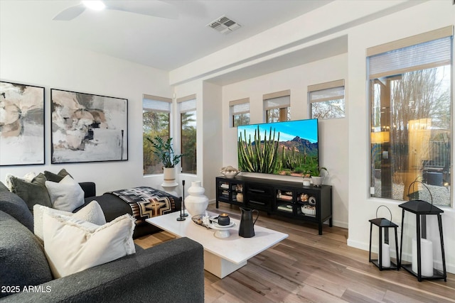 living area featuring baseboards, wood finished floors, visible vents, and ceiling fan