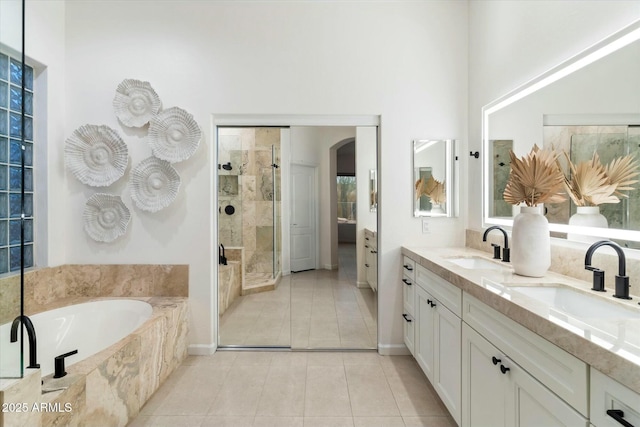 bathroom featuring tile patterned flooring, a stall shower, a bath, and a sink