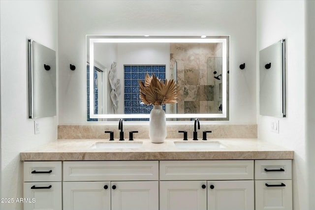 bathroom with double vanity, tiled shower, and a sink