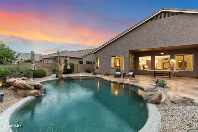 pool at dusk with a fenced in pool, a patio, a ceiling fan, and fence