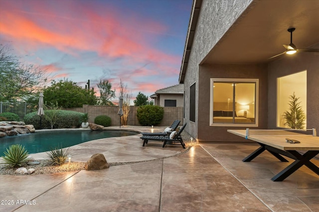 pool at dusk featuring a ceiling fan, a patio area, a fenced in pool, and a fenced backyard