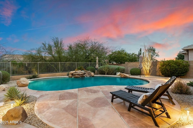 pool at dusk with a patio area, a fenced in pool, and a fenced backyard