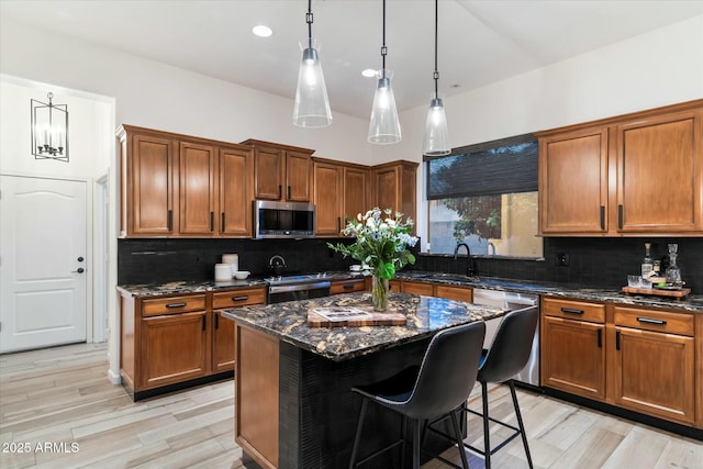 kitchen featuring a center island, a breakfast bar area, dark stone counters, stainless steel appliances, and a sink