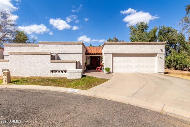 view of front of property featuring an attached garage, concrete driveway, stucco siding, and a tile roof