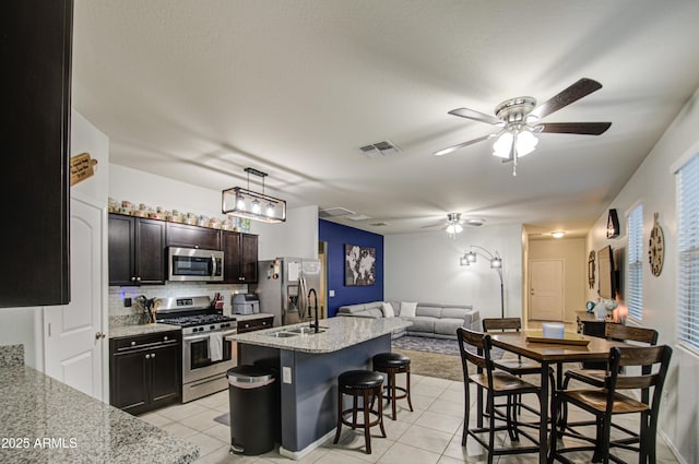 kitchen featuring visible vents, open floor plan, a kitchen bar, light tile patterned floors, and stainless steel appliances