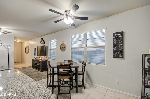 dining area with light tile patterned flooring, baseboards, and ceiling fan