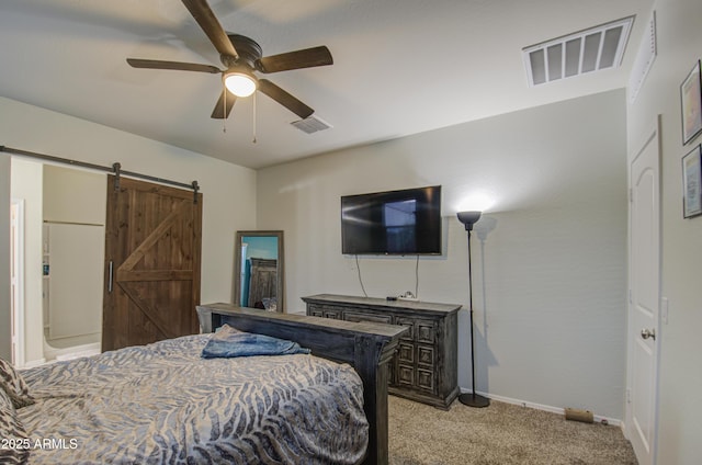 bedroom featuring light carpet, visible vents, baseboards, and a barn door