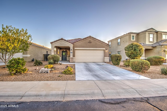 view of front of property with stucco siding, a garage, driveway, and a tiled roof