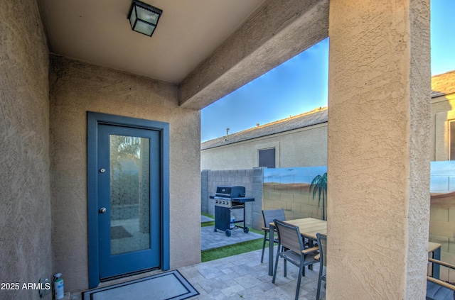 entrance to property with outdoor dining space, stucco siding, a patio, and fence