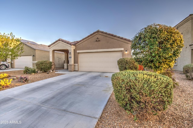 mediterranean / spanish-style house featuring stucco siding, driveway, a tile roof, and a garage