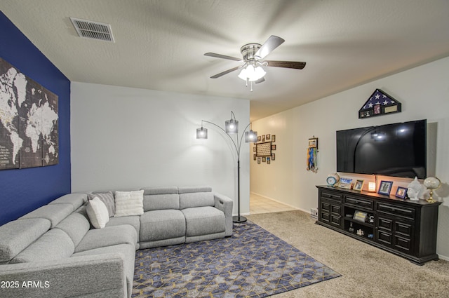 carpeted living area featuring visible vents, a textured ceiling, and ceiling fan