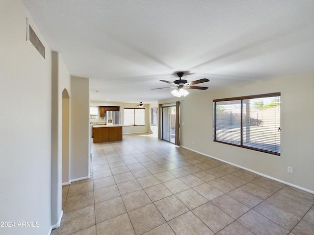 unfurnished living room with light tile patterned floors and ceiling fan