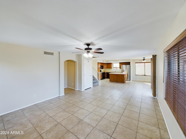 unfurnished living room with ceiling fan and light tile patterned floors