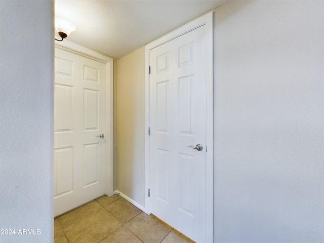 corridor featuring light tile patterned floors and a textured ceiling