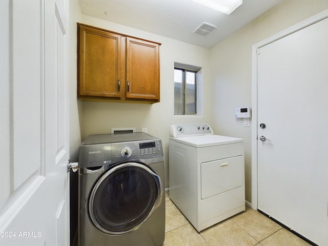 washroom with cabinets, light tile patterned floors, and washer and clothes dryer