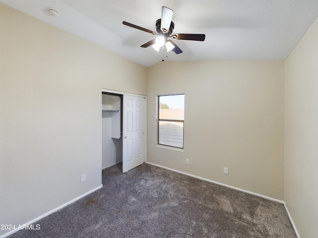 unfurnished bedroom featuring dark carpet, a closet, vaulted ceiling, and ceiling fan