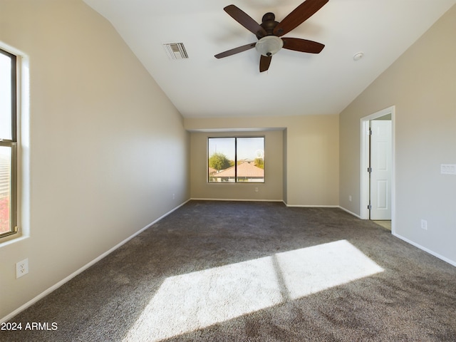 empty room with ceiling fan, vaulted ceiling, and dark colored carpet