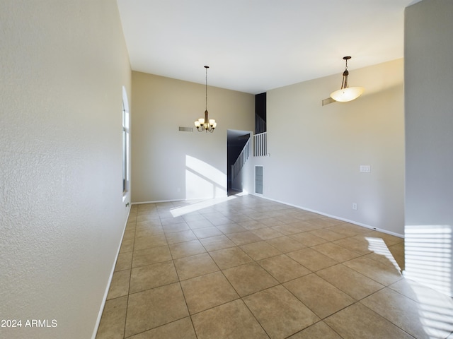 tiled empty room featuring an inviting chandelier