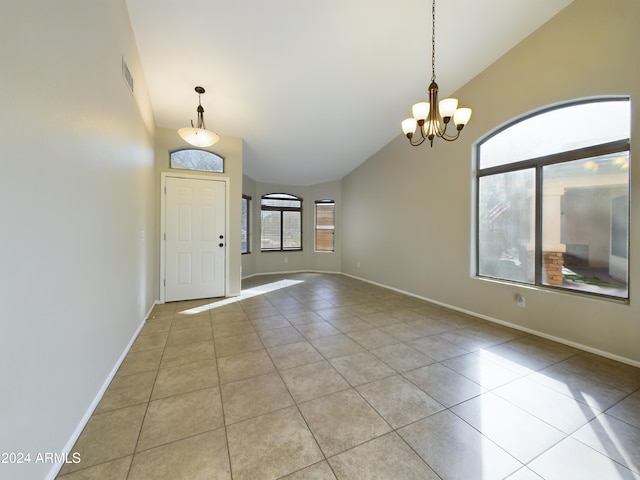 foyer entrance with light tile patterned flooring, lofted ceiling, and a notable chandelier