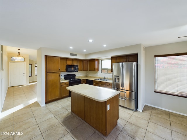 kitchen with sink, black appliances, decorative light fixtures, a center island, and light tile patterned flooring