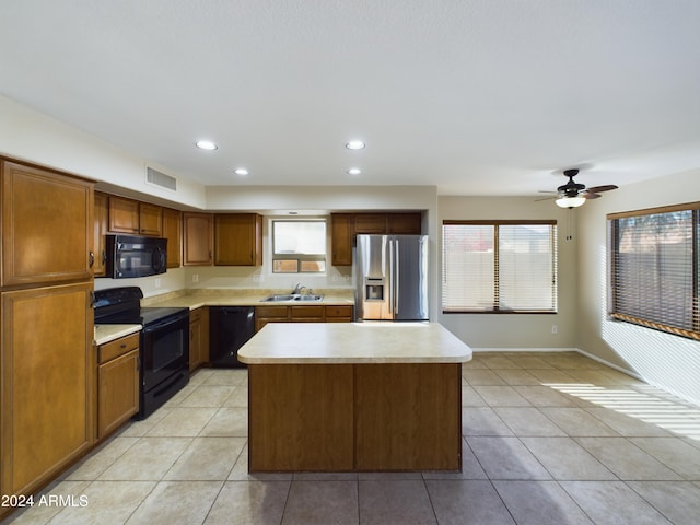 kitchen featuring sink, a kitchen island, black appliances, and light tile patterned floors