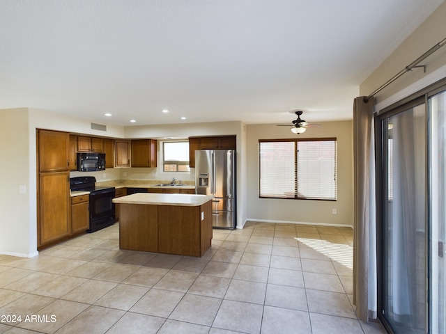 kitchen with black appliances, a center island, a healthy amount of sunlight, and sink