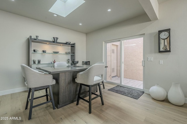 dining area featuring light hardwood / wood-style flooring and a skylight