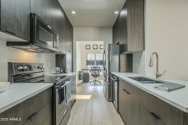 kitchen featuring dark brown cabinetry, sink, light hardwood / wood-style flooring, and stainless steel appliances