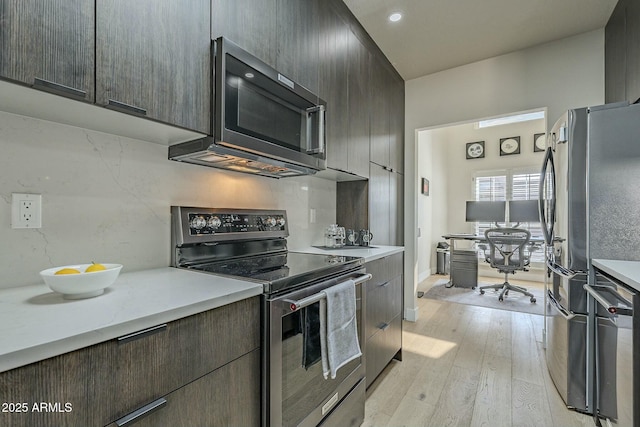 kitchen with backsplash, dark brown cabinets, light hardwood / wood-style floors, and appliances with stainless steel finishes