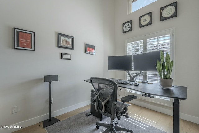 office space featuring a towering ceiling and light hardwood / wood-style flooring