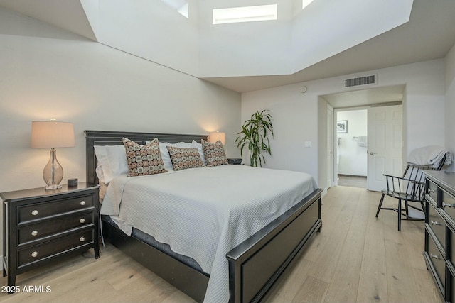 bedroom featuring a towering ceiling and light hardwood / wood-style flooring