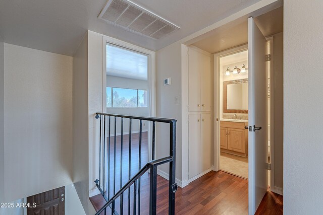 2233 W Farmdale Ave Unit 2, Mesa, AZ 85202 - corridor featuring dark wood-style floors, a sink, visible vents, baseboards, and an upstairs landing