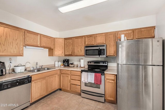 kitchen with light tile patterned floors, appliances with stainless steel finishes, light countertops, and a sink