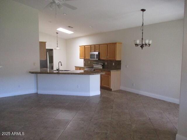 kitchen with decorative backsplash, pendant lighting, a sink, ceiling fan with notable chandelier, and stainless steel appliances