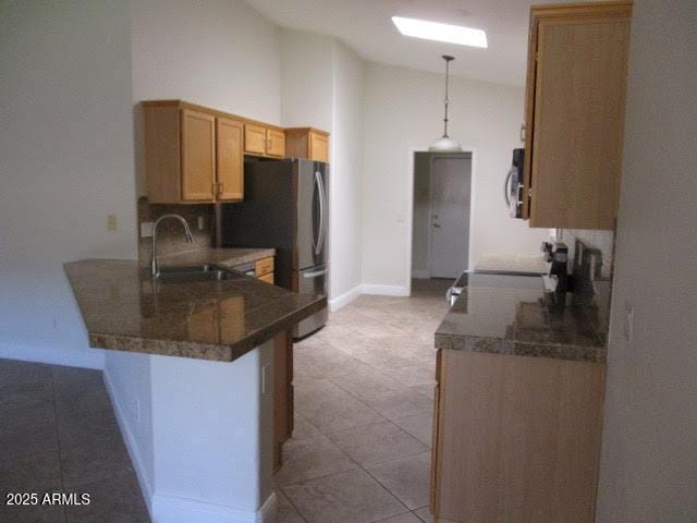kitchen with a kitchen bar, decorative light fixtures, a sink, a peninsula, and tile counters