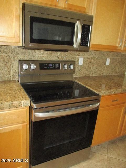 kitchen with light tile patterned floors, backsplash, stainless steel appliances, and tile countertops