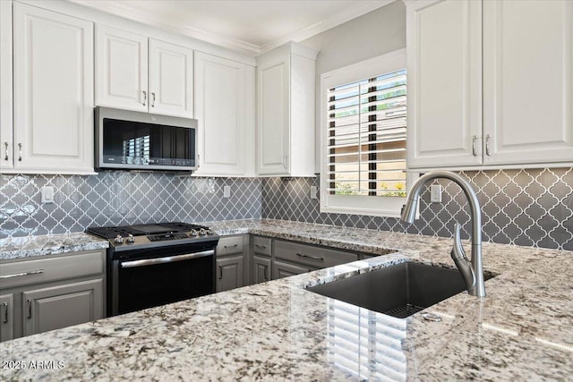 kitchen with white cabinets, decorative backsplash, appliances with stainless steel finishes, and sink